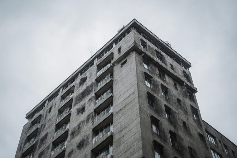 A tall concrete residential tower seen from street level against a pale sky